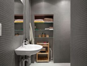 Modernt badrum med grå mosaik, handfat och en hängande handduk på väggen.